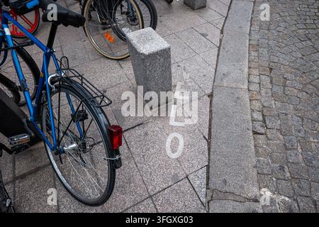 Velo-Text auf grauem Kopfsteinpflaster und Gehweg mit einem geparkten blauen Fahrrad, der das urbane Radfahren und umweltfreundliche Verkehrsmittel in Paris zeigt Stockfoto