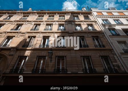 Klassische Haussmann-Apartmenthäuser säumen eine Straße in Paris, Frankreich, mit kunstvollen Steinfassaden, verzierten Balkonen und offenen Fenstern Stockfoto