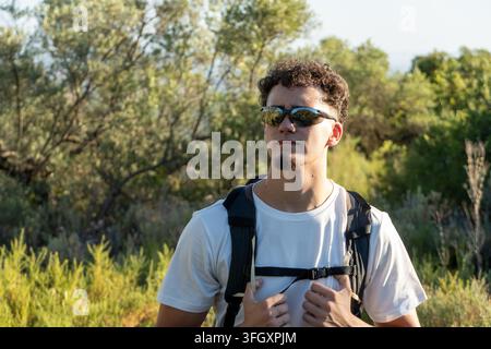 Mann wandert in der Natur und trägt eine Sonnenbrille und einen Rucksack Stockfoto