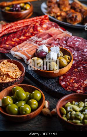 Sortiment an gepökeltem Fleisch und Antipasti, serviert auf einem rustikalen Holzbrett Stockfoto