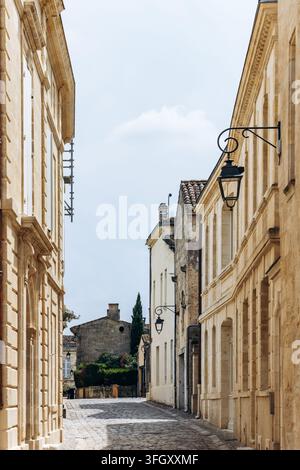 Ruhige Kopfsteinpflasterstraße gesäumt von Steinbauten und kunstvollen Wandlaternen im historischen Zentrum von Saint Emilion, Nouvelle-Aquitaine, Frankreich Stockfoto