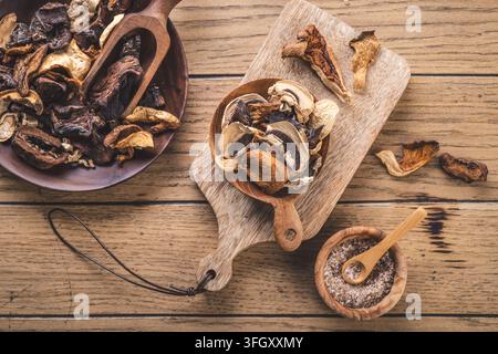 Getrocknete Waldpilze in hölzernen Löffeln und Schüsseln auf einem rustikalen Tisch Stockfoto