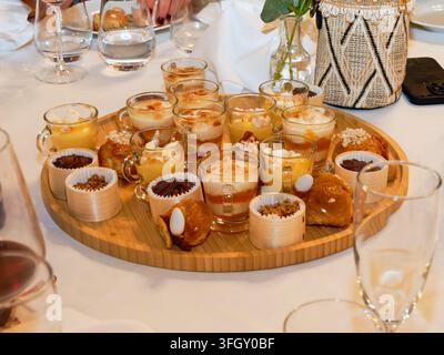 Verschiedene Miniatur-Desserts und Gebäckstücke, die auf einem Serviertablett bei einer formellen Empfangsanordnung angeordnet sind Stockfoto