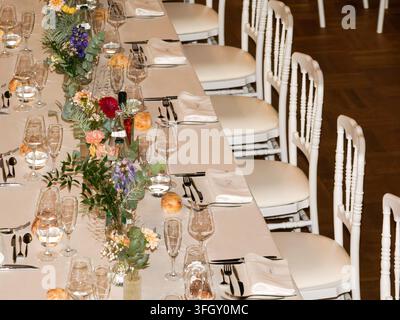 Elegante Banketttisch-Garnitur mit Blumendekoration und weißen Stühlen bei einer formellen Veranstaltung Stockfoto