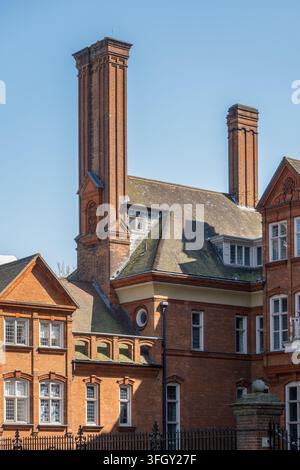 Verschnörkelte viktorianische Ziegelschornsteine und Giebeldächer erheben sich über einem roten Backsteingebäude im Zentrum Londons, England, UK Stockfoto