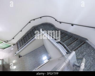 Breitwinkel-, Hochwinkelaufnahme, die eine zeitgenössische architektonische Treppe mit polierten grauen Marmorstufen, weißen minimalistischen Wänden und einem Co Stockfoto