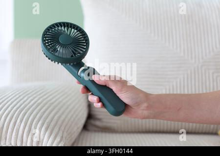 Frau schaltet einen Miniventilator im Innenraum ein, Nahaufnahme Stockfoto