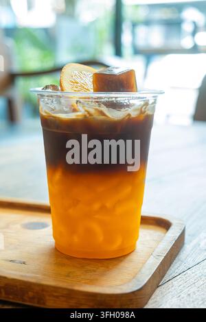 Bumble-Kaffee aus geschichtetem Espresso und frischem Orangensaft, serviert mit Eis, Orangenscheibe und Kaffee-Eiswürfel in einem thailändischen Café. Spezialkaffee Stockfoto