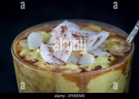 Grüner Avocado Smoothie mit schwarzem Kaffee und Kokosnusschips während des Frühstücks, Nahaufnahme Stockfoto