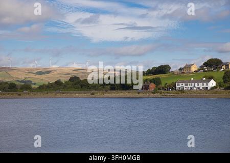 Panoramablick über die glitzernden Gewässer des Hollingworth Lake zu fernen Windrädern an den Penninenhügeln, Rochdale, UK. Stockfoto