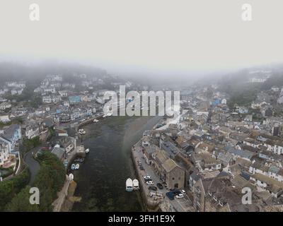Eine Luftbilddrohne fängt die malerische Hafenstadt Looe in Cornwall, England, ein, die in dichten, stimmungsvollen Nebel gehüllt ist. Stockfoto