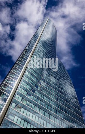 Architektonisches Detail eines gebogenen Glasbüroturms vor einem blauen Himmel in Madrid Stockfoto