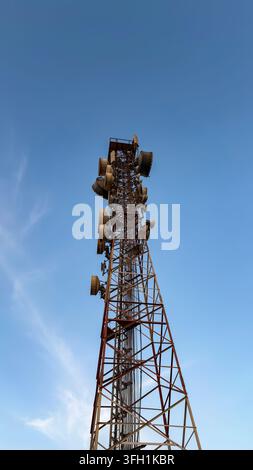Hoher Telekommunikationsmast mit Antennen vor einem blauen Himmel. Stockfoto