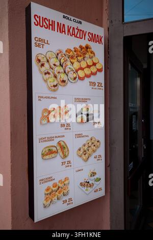 Die Werbetafel eines Restaurants zeigt Fotos und polnische Preise für verschiedene Sushi-Sets an einer Innenstadt-Fassade. Stockfoto