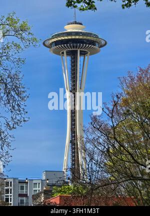Niedrigwinkelaufnahme des Space Needle, das sich gegen einen blauen Himmel erhebt und von Bäumen in Seattle, Washington, eingerahmt wird. Stockfoto