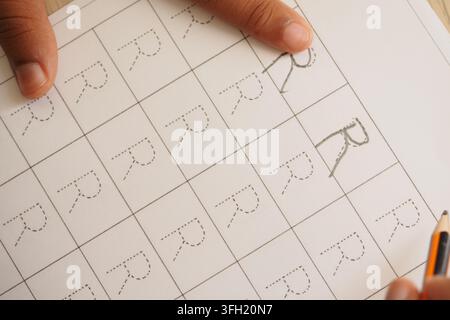 Lernen, Buchstaben mit dem Bleistift auf einem Übungsblatt zu schreiben Stockfoto