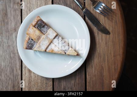 Scheibe Apfelkuchen auf einem weißen Teller, der auf einem Holztisch steht Stockfoto