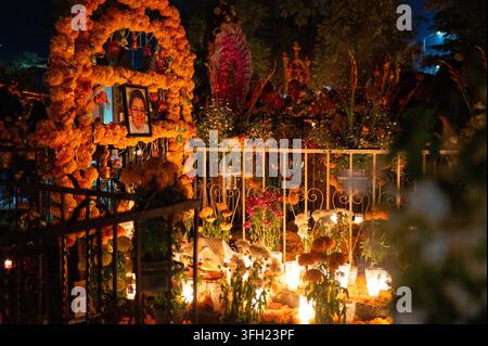 Traditionelles Tag-der-Toten-Grab, dekoriert mit reichlichen Ringelblumen, Kerzen, Blumenarrangements, persönlichen Opfergaben und einem gerahmten Porträt von Stockfoto