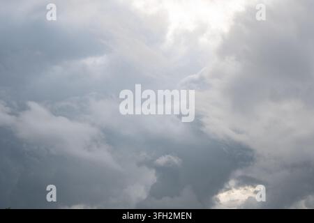 Ein dramatischer Blick auf dicke graue Wolken, die den Himmel bedecken, mit hellem Sonnenlicht, das durch die obere rechte Ecke bricht. Die stürmische bewölkte Atmosphäre ersch Stockfoto