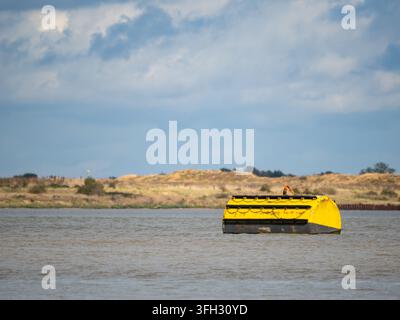 Gelbe Markierungsboje auf offenem Wasser nahe einem Flussufer, Gravesend, Kent, UK. Stockfoto
