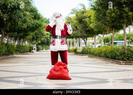 Verlorener Weihnachtsmann überprüft Smartphone für Wegbeschreibungen in der Stadt Stockfoto