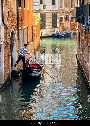 Gondel auf einem schmalen Kanal in Venedig, Italien, umgeben von historischen Gebäuden Stockfoto