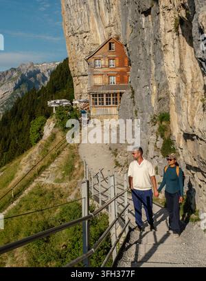 Ein Paar genießt einen gemütlichen Spaziergang entlang eines schönen Pfades am Wildkirchli Ascher Ebenalp in der Schweiz, umgeben von atemberaubenden Klippen und üppiger Vegetation. Stockfoto