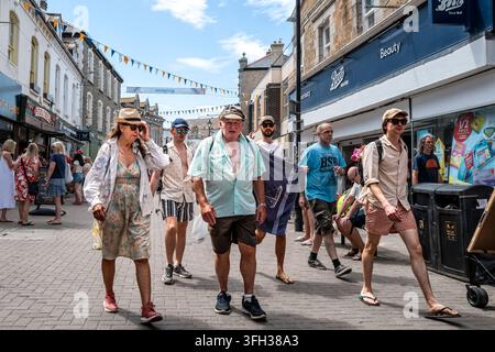 Besucher, Urlauber, die entlang der Bank Street in sehr heißem sonnigem Wetter im Zentrum von Newquay in Cornwall in Großbritannien spazieren. Stockfoto