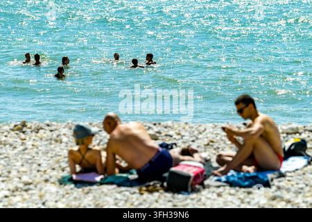 Le Havre (Normandie, Nordwestfrankreich): drei Personen sonnen sich an einem Kieselstrand und andere schwimmen im Meer Stockfoto