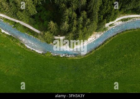 Eine Drohnenaufnahme des Fußweges von Einöd zum Schütthof in Salzau nahe Neukirchen am Großvenediger. Der Weg windet sich idyllisch entlang des türkisblauen Untersulzbach-Baches, eingebettet zwischen grünen Wiesen und dichtem Wald, und bietet einen Blick aus der Vogelperspektive auf die ruhige Naturlandschaft des Oberpinzgaus. Mai 2026 Stockfoto