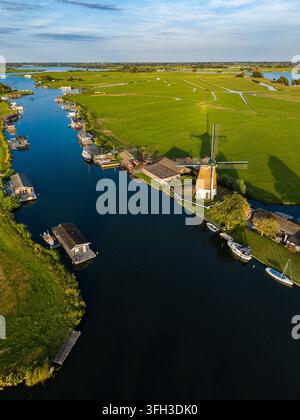 Hochwinkel-Vertikal-Luftbild vom Drohnenflug, das die weitläufige Landschaft einfängt, in der die historische De Faljeril-Grundsegler-Polderwindmühle steht Stockfoto