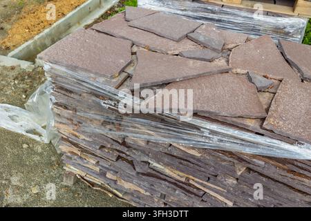 Gestapelte unregelmäßige Steinplatten auf Palette für die Installation von Gartenwegen, Wohnlandschaftsgestaltung und Hartflächengestaltung. Stockfoto
