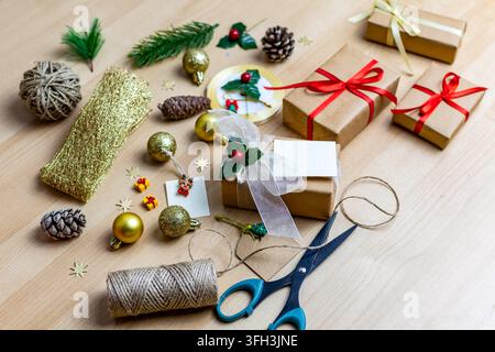 Oberblick über handgemachte Weihnachtsgeschenke mit Verpackungsmaterial auf einem Holztisch Stockfoto