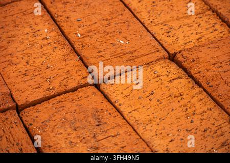 Nahaufnahme von massiven roten Ziegelsteinen aus Ton, die draußen im natürlichen Sonnenlicht ordentlich ausgelegt sind, mit rauen, porösen Oberflächendetails und Textur. Sichtb Stockfoto
