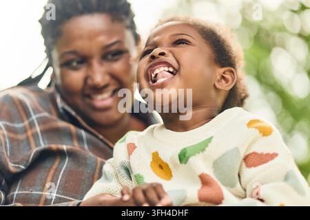 Glückliche schwarze Mutter und Tochter lachen zusammen im Freien Stockfoto
