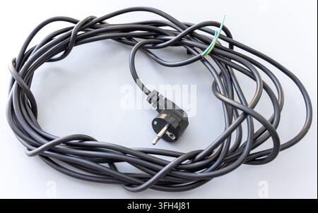 Ein gewundener schwarzer elektrischer Netzkabel hat einen Stecker und freiliegende Drähte Stockfoto