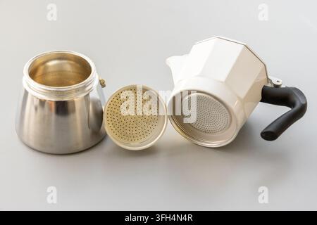 Ein weißer und silberner Moka-Kaffeebecher ist auf einer grauen Oberfläche zerlegt Stockfoto