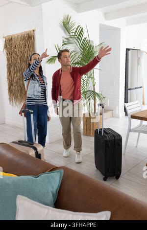 Afrikanisches Paar steht und zeigt auf eine helle Raum mit Koffern in roter Jacke und gestreiftem Oberteil Stockfoto