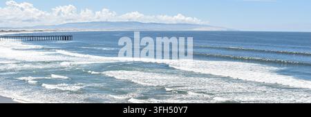 Großer felsiger Meeresfelsen, umgeben von rollenden Ozeanwellen und weißem Schaum an einer malerischen Pazifikküste. Stockfoto