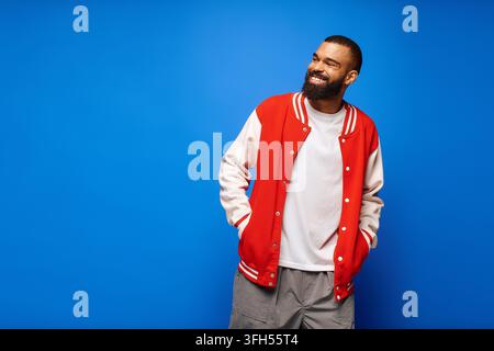 Ein junger, gutaussehender Mann in einer roten Jacke lächelt selbstbewusst. Stockfoto
