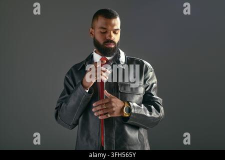 Ein junger gutaussehender afroamerikanischer Mann trägt stilvolle Kleidung und rückt seine Krawatte zurecht. Stockfoto