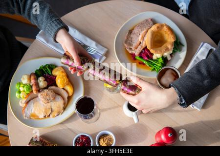 Zwei Personen genießen ein festliches Mahl mit farbenfrohen Tellern und Getränken in einer warmen Atmosphäre. Stockfoto