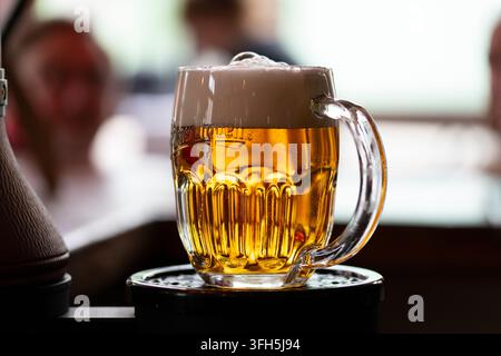 Erfrischendes goldenes Bier, serviert in einem gefrorenen Krug in einer lebhaften Kneipenatmosphäre Stockfoto