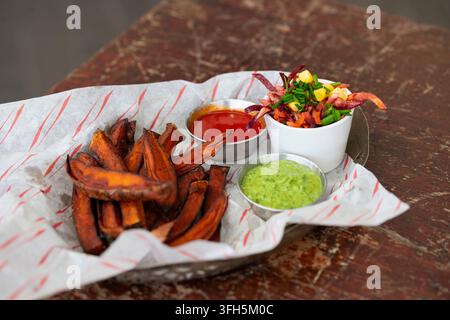 Köstliche Süßkartoffel Pommes, serviert mit lebhaften Dipsaucen Stockfoto