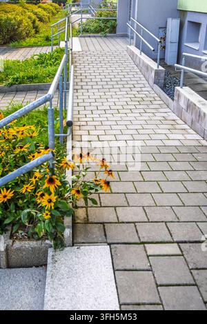 Zugänglicher Rampenweg mit Geländern führt zum Gebäudeingang Stockfoto