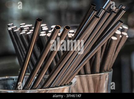Ein Büschel schwarzer Trinkhalme, die in klaren Glasbehältern gehalten werden. Stockfoto