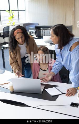Afroamerikanische Frauen, die sich vorbeugen und einen offenen Laptop an einem modernen Bürotisch mit Notizblock überprüfen. Zusammenarbeit, Teamarbeit, Brainstorming, Mentoring, s Stockfoto