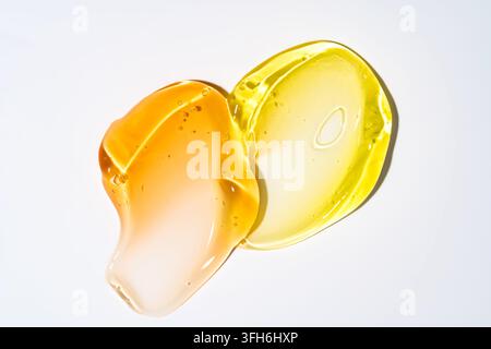 Transluzente goldene und bernsteinfarbene kosmetische Gelschmiere mit glänzender Textur und Luftblasen, isoliert auf einem sauberen weißen Hintergrund für Hautpflege und Schönheit Stockfoto