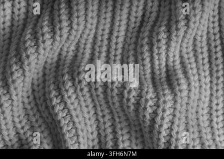 Nahaufnahme, Makro von zerknittertem grauem Strickstoff mit sichtbaren Falten, Knitter und weichen Wellen. Weiche Wolltextur mit detaillierten Maschen und Falten, nat Stockfoto