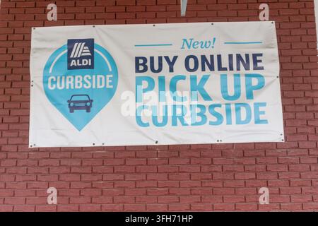 Banner an einer roten Backsteinmauer wirbt für aldi Online-Shopping und Abholservice am Straßenrand. Stockfoto